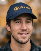 Man wearing a blue cap with 'Gooey Duck' text against a blurred background